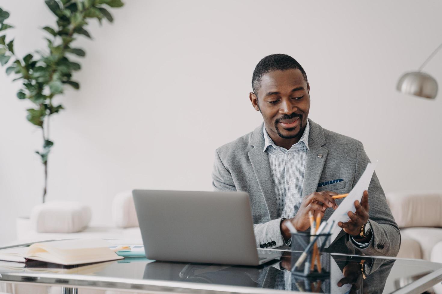 Businessman has paperwork. Happy man has video call on laptop and pointing to data papers. photo