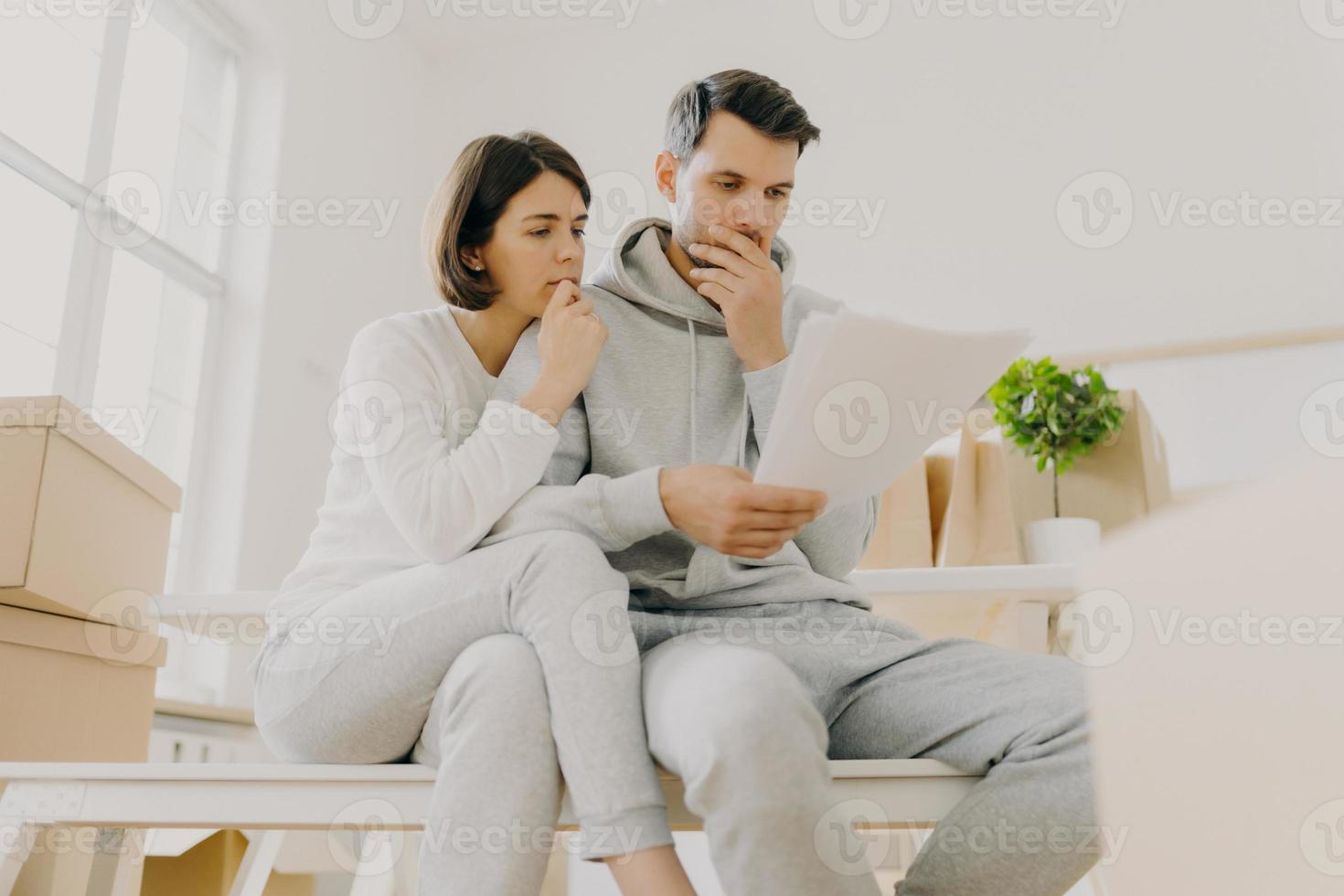 foto de una mujer y un hombre molestos que tienen facturas domésticas impagas, tienen papeles, se sientan en una habitación espaciosa, administran las finanzas, revisan la cuenta bancaria, tienen que pagar impuestos, se mudan a un apartamento nuevo, hacen el papeleo juntos