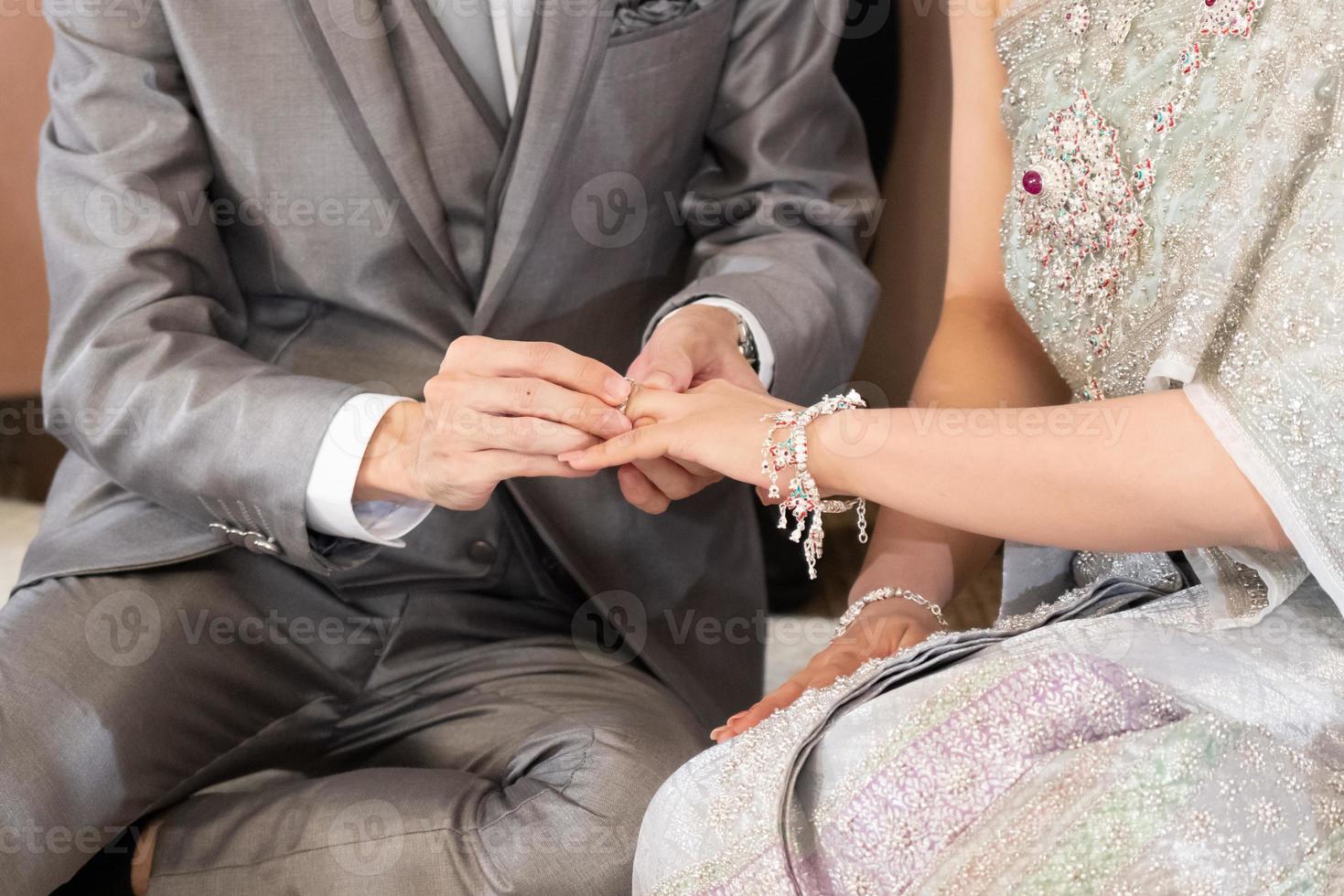 The groom put a wedding ring into a bride finger inThai Wedding Concept photo