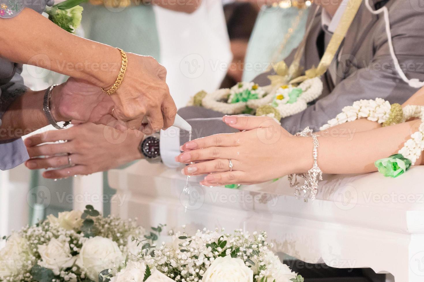 Hands pouring blessing water in water pouring ceremony photo