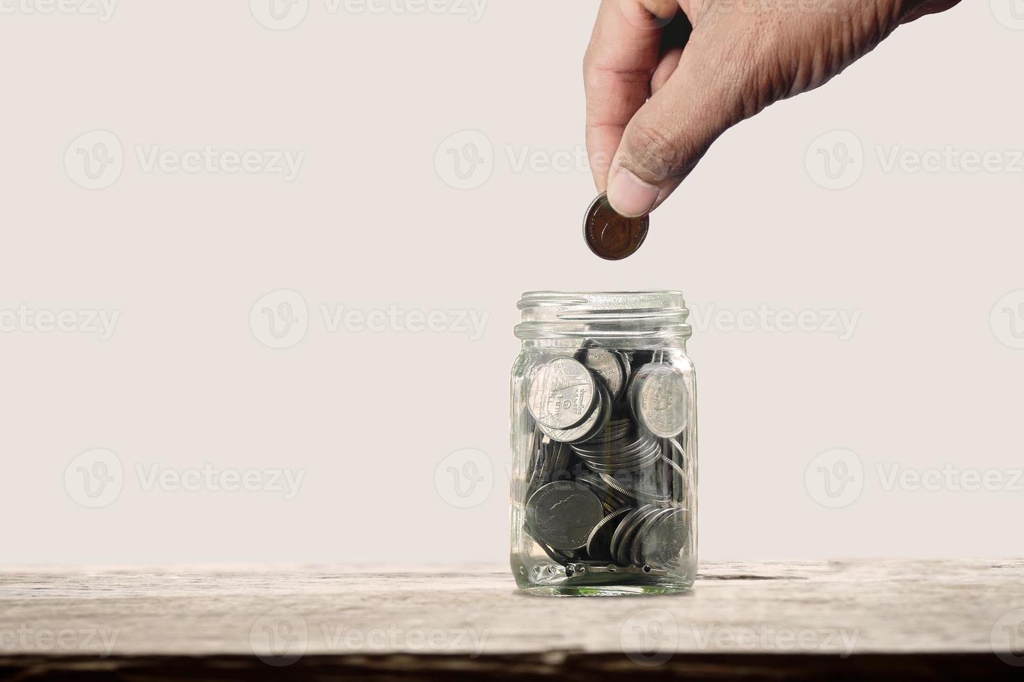 Young man holding coins putting in The bottle glass. concept saving money or tax save for financial accounting and business. photo