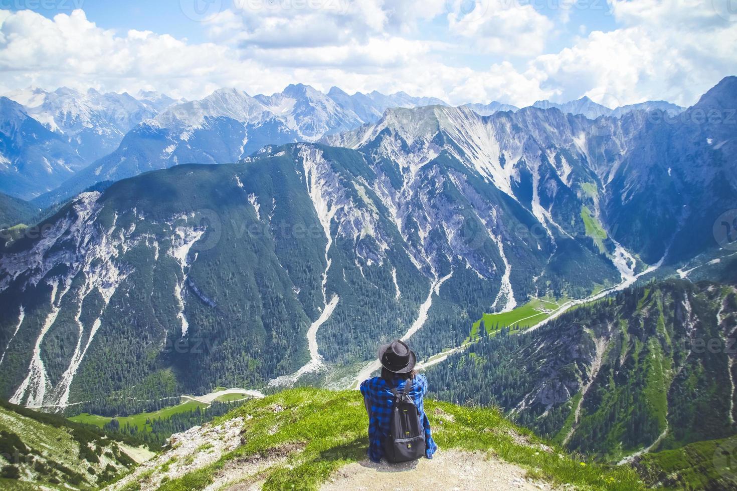 Woman traveller sitting admiring the scenery of the Alps mountains. photo