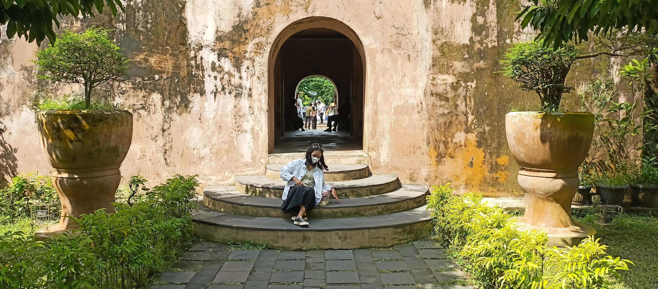 Jogjakarta - june 5, 2022  - portrait of an asian woman in a green dress near a sari garden pond photo