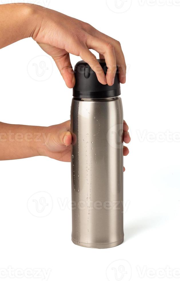 Hands are holding on the lid of the water bottle to twist and open the silver glossy metal vacuum thermo tumbler flask isolated on a white background, Hot water bottle, Portable device. photo