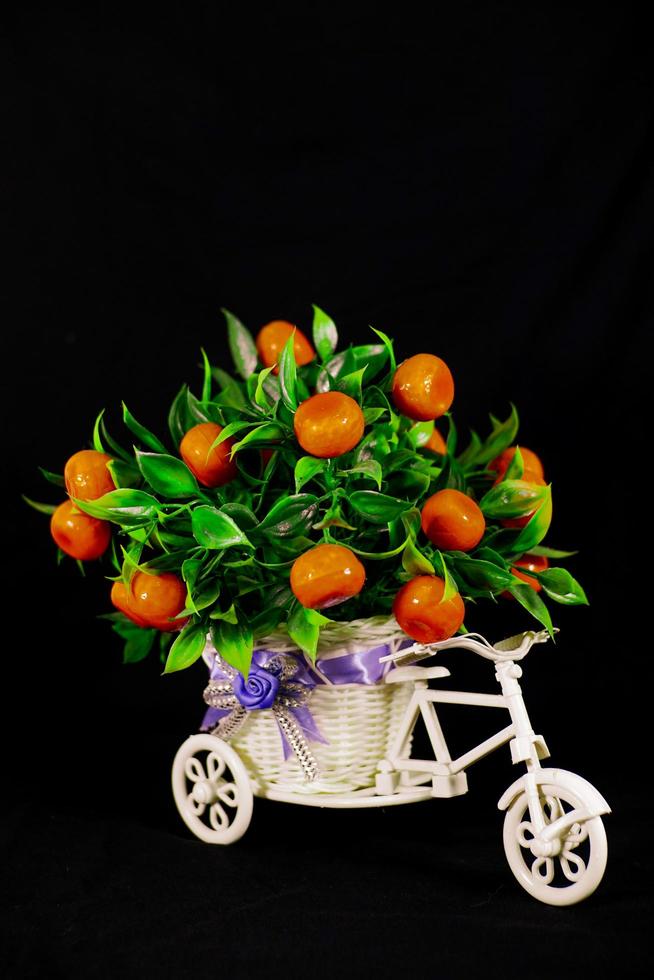 house decoration in the form of an orange tree on a bicycle in the photo on a black background May 27, 2022