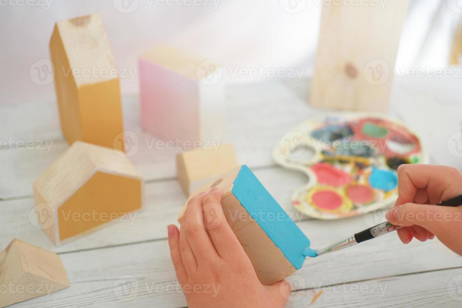 teenager girl's hands painting wooden toy house in blue. hobby or leisure during quarantine. photo