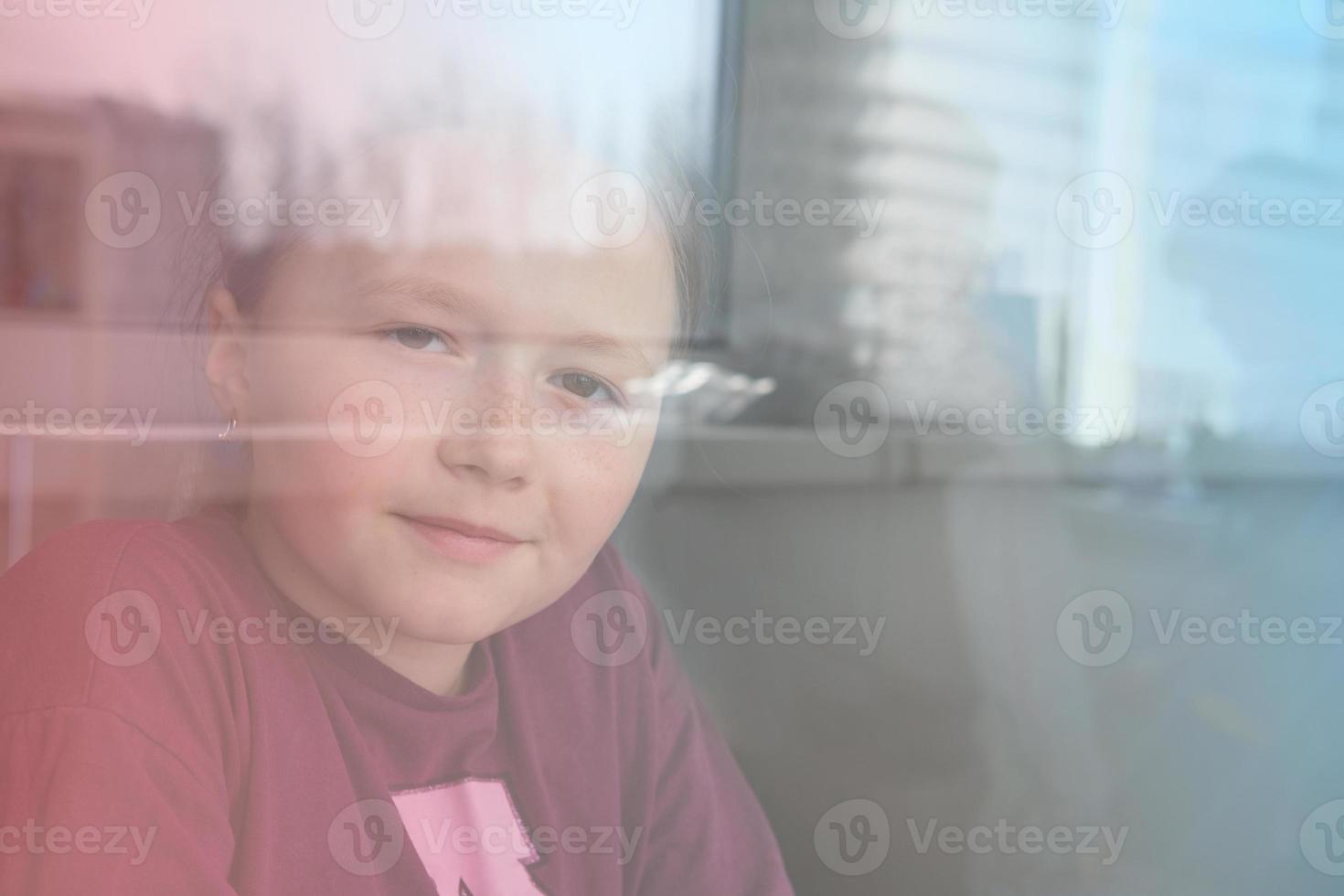 beautiful teenage girl looking through the window. photo