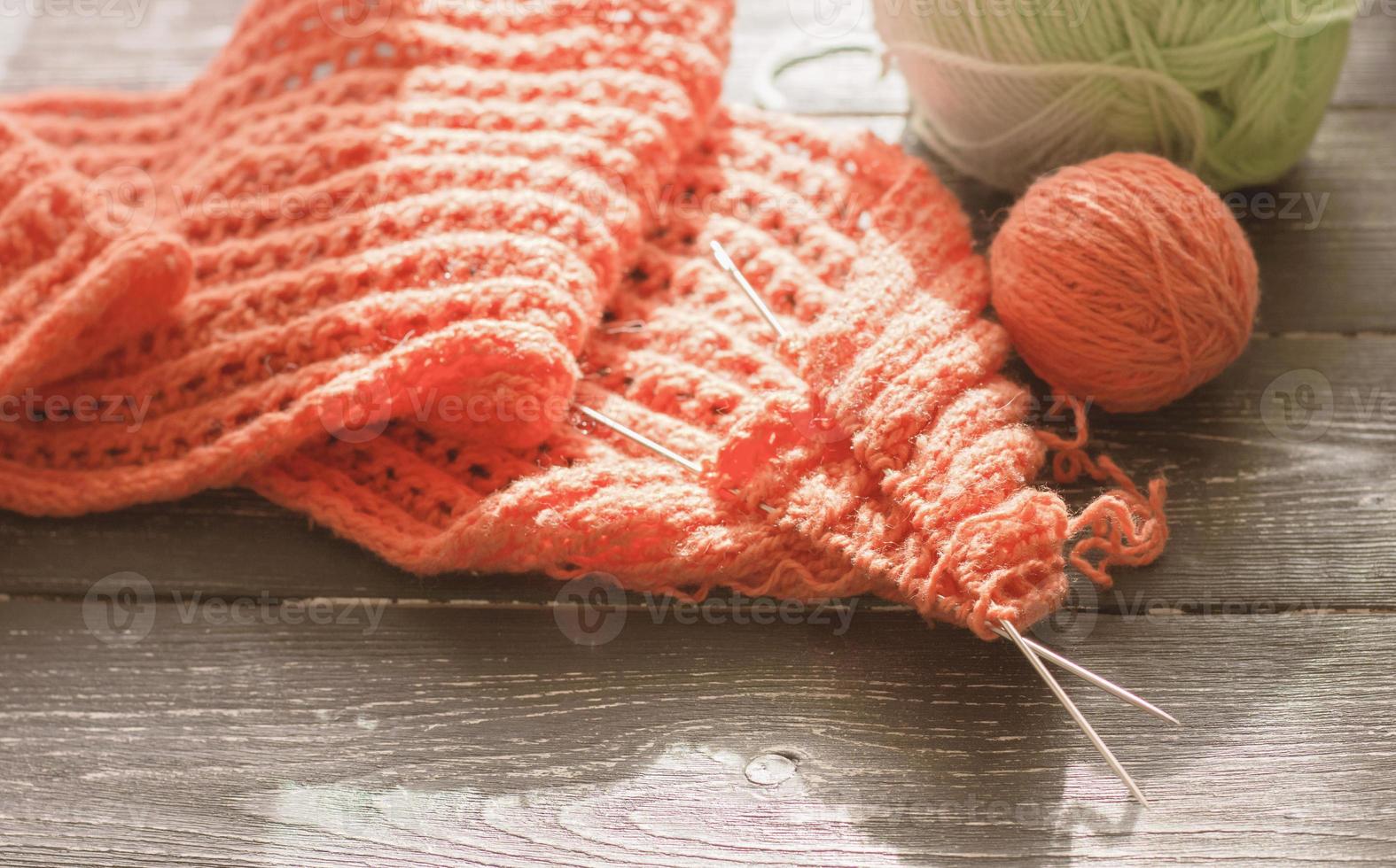 knitting needles, orange yarn and textured knitted fabric in progress. photo