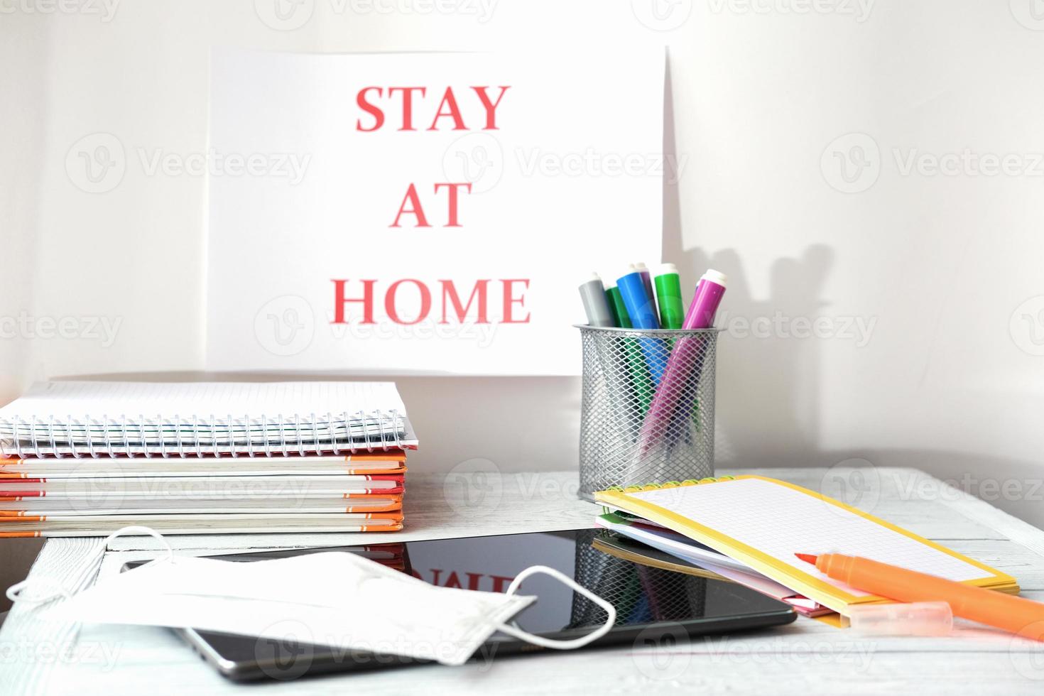 stay at home concept. pc tablet, medical mask, books and markers on wooden table. photo