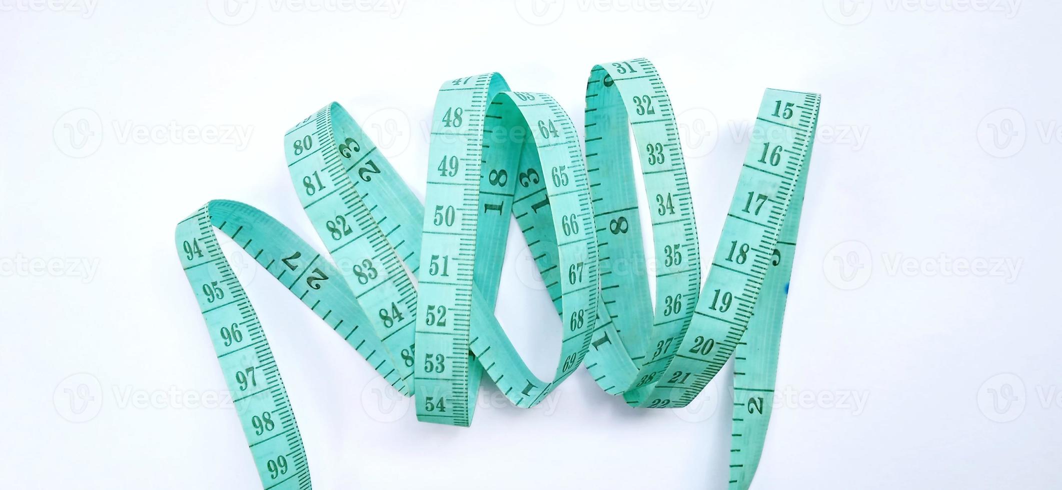 Old wrinkled green rubber tape measure with negative space. Rubber tape measure isolated on the gray white background. Useful for sewing cloth or fabric. photo