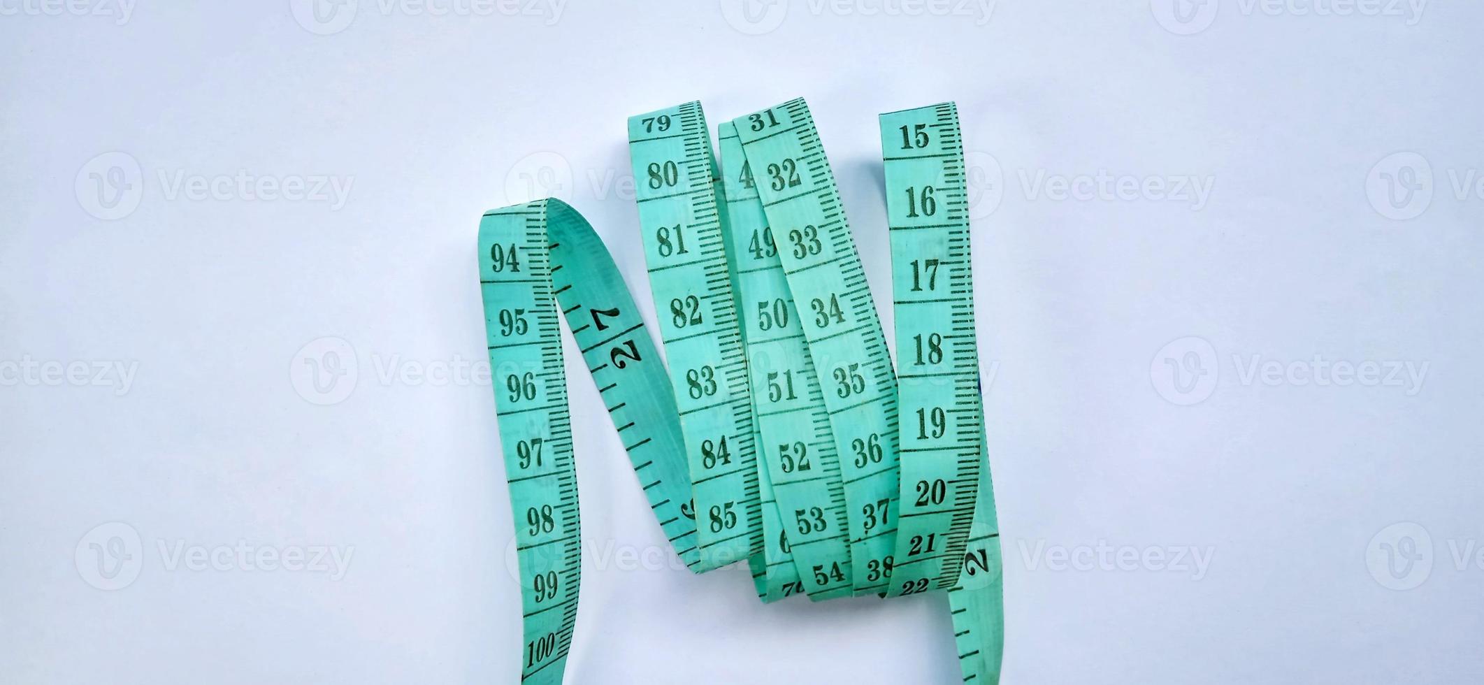 Old wrinkled green rubber tape measure with negative space. Rubber tape measure isolated on the gray white background. Useful for sewing cloth or fabric. photo