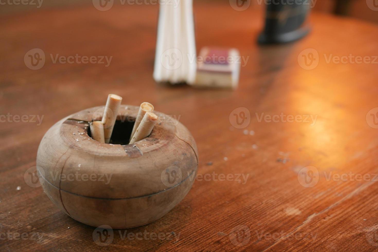 Close up burning cigarette in ashtray on table photo