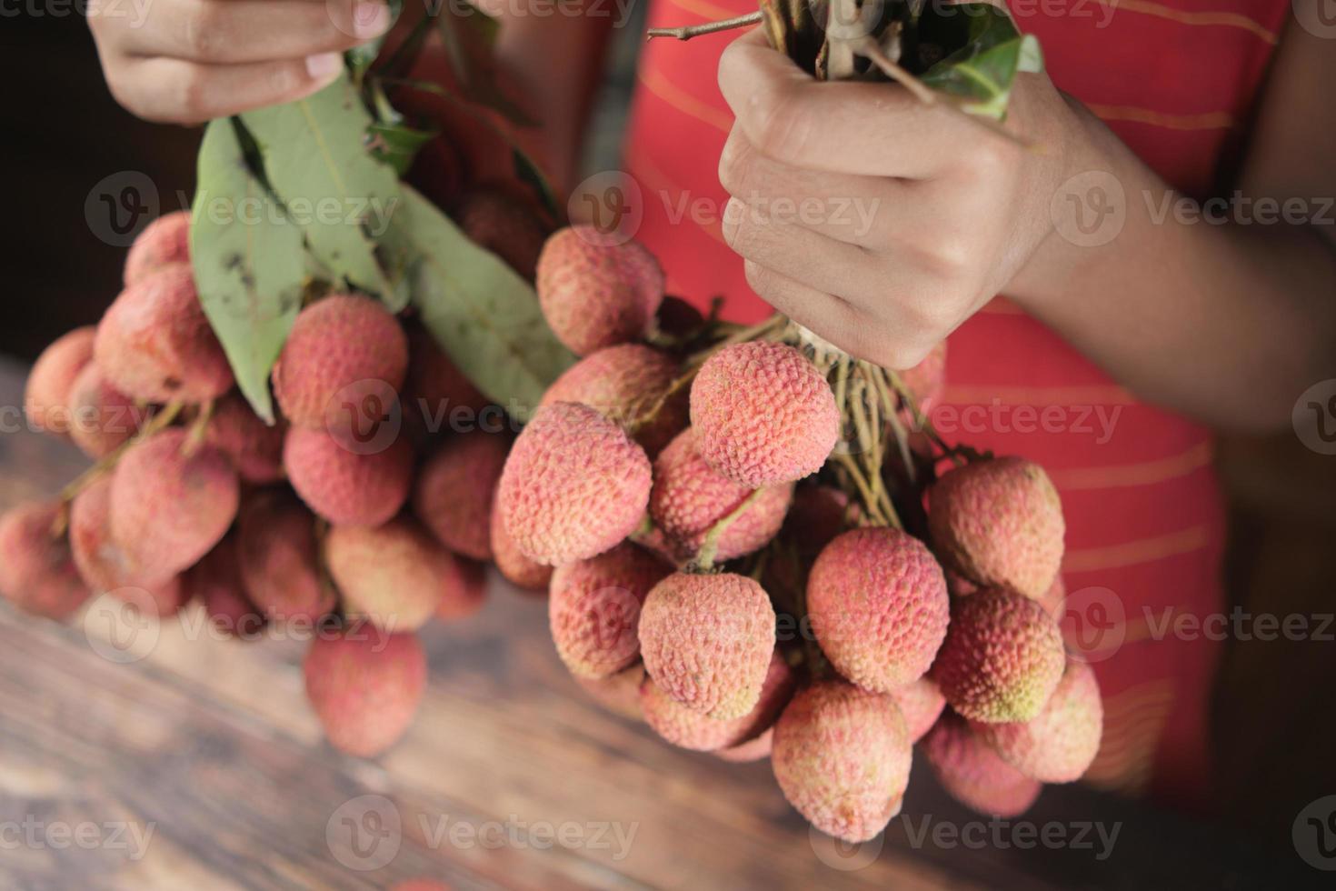 young men holding Lychee fruit close up photo