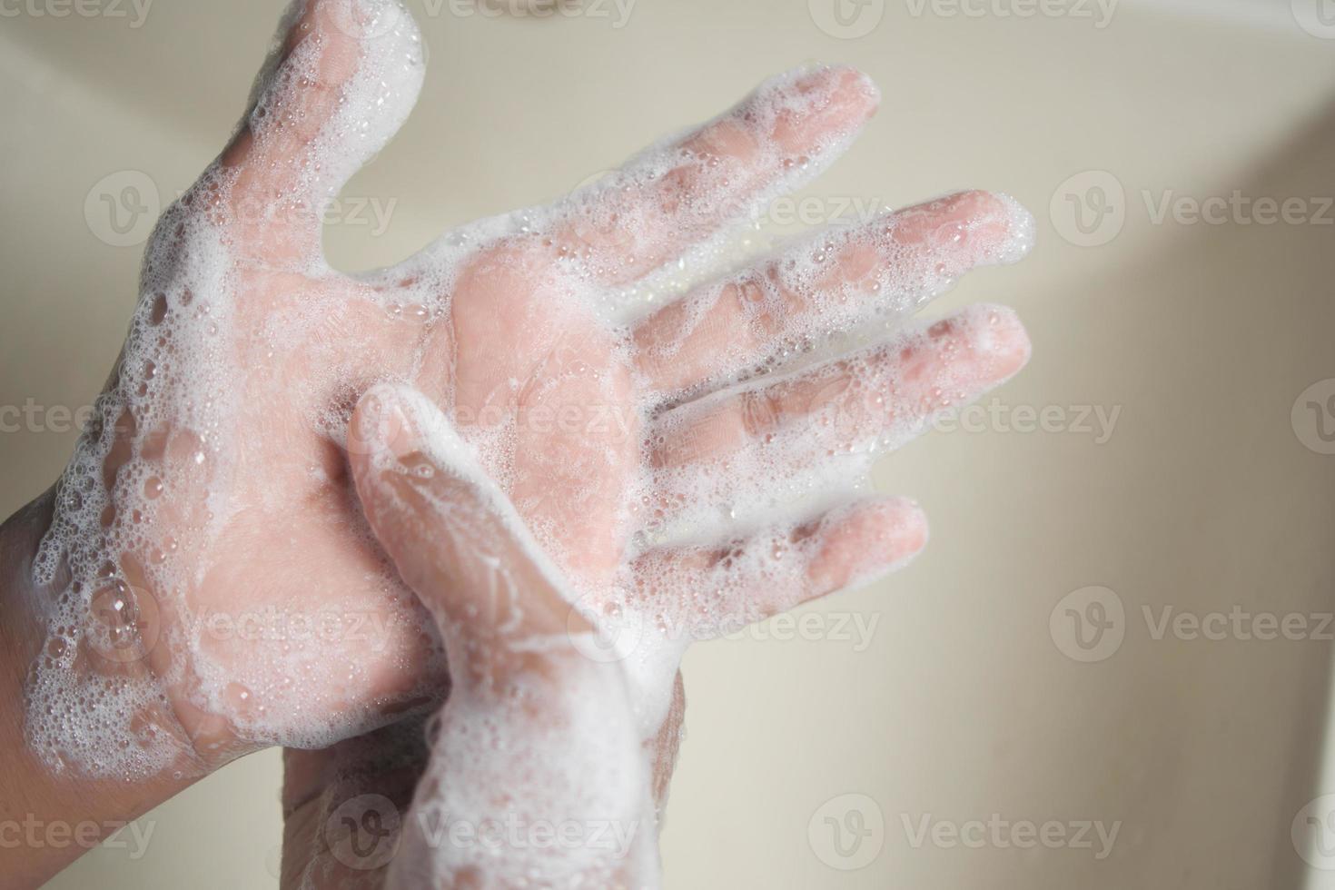 young man washing hands with soap warm water photo