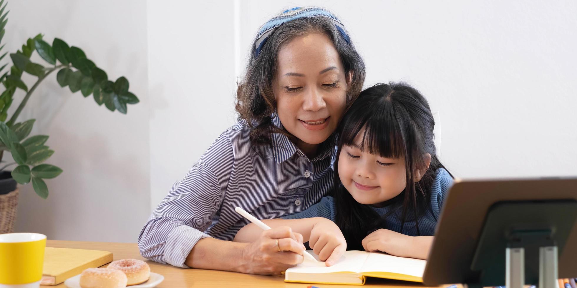 happy asian family grandmother reading to granddaughter child book at home photo