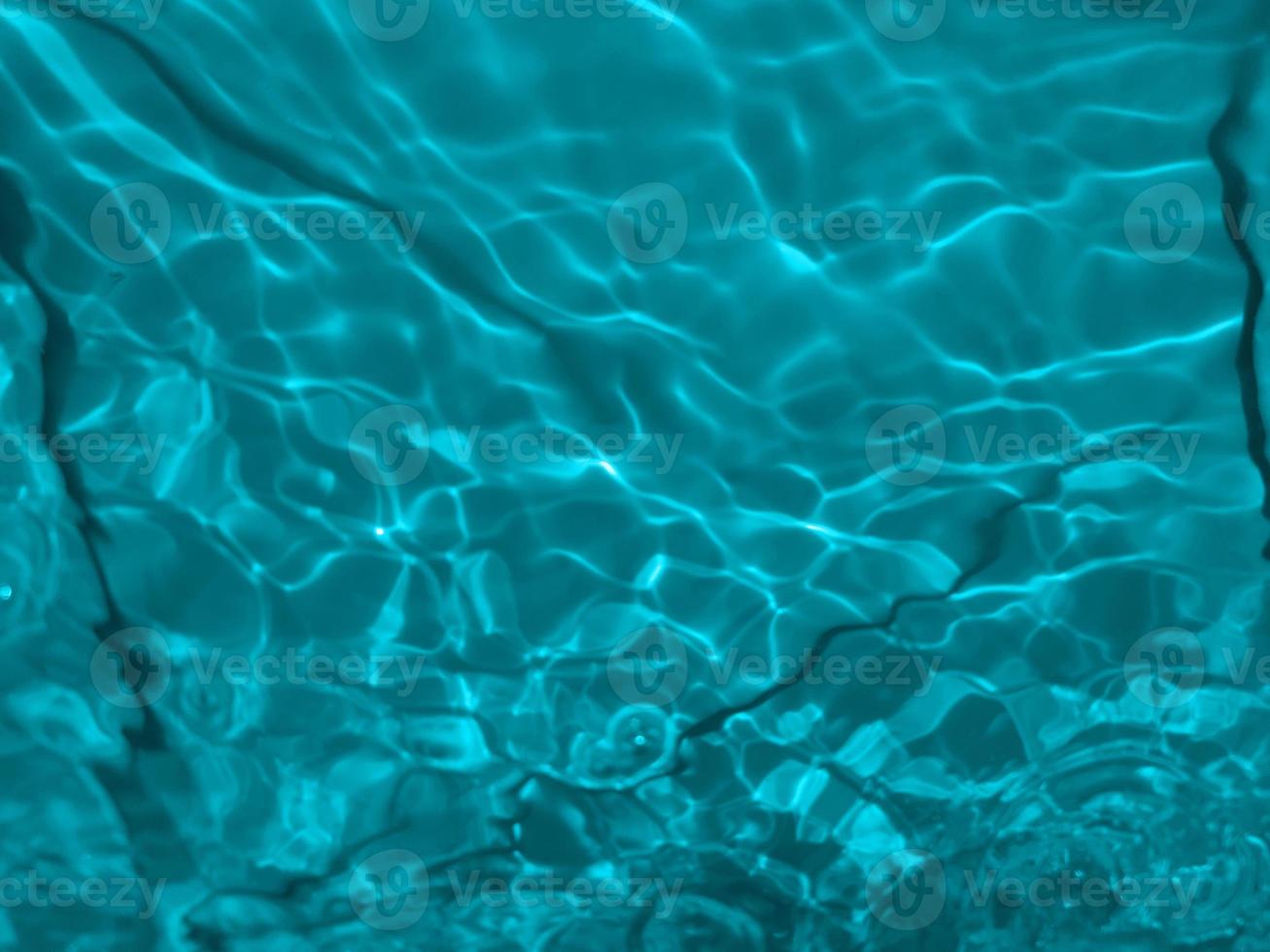 Defocus blurred transparent blue colored clear calm water surface texture with splashes and bubbles. Trendy abstract nature background. Water waves in sunlight. Blue water background. photo