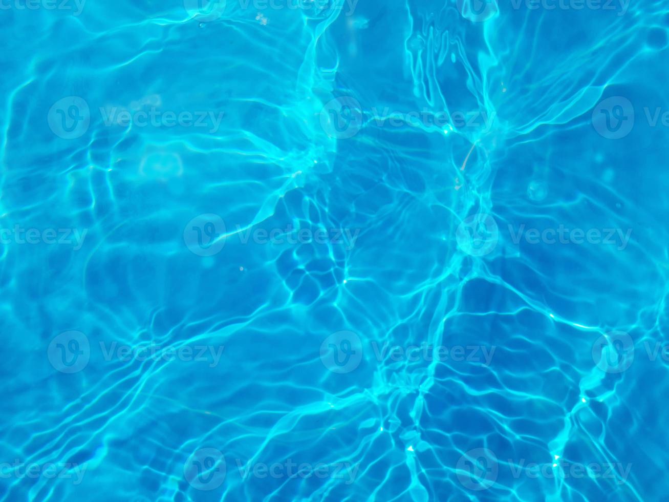 Defocus blurred transparent blue colored clear calm water surface texture with splashes and bubbles. Trendy abstract nature background. Water waves in sunlight. Blue water background. photo