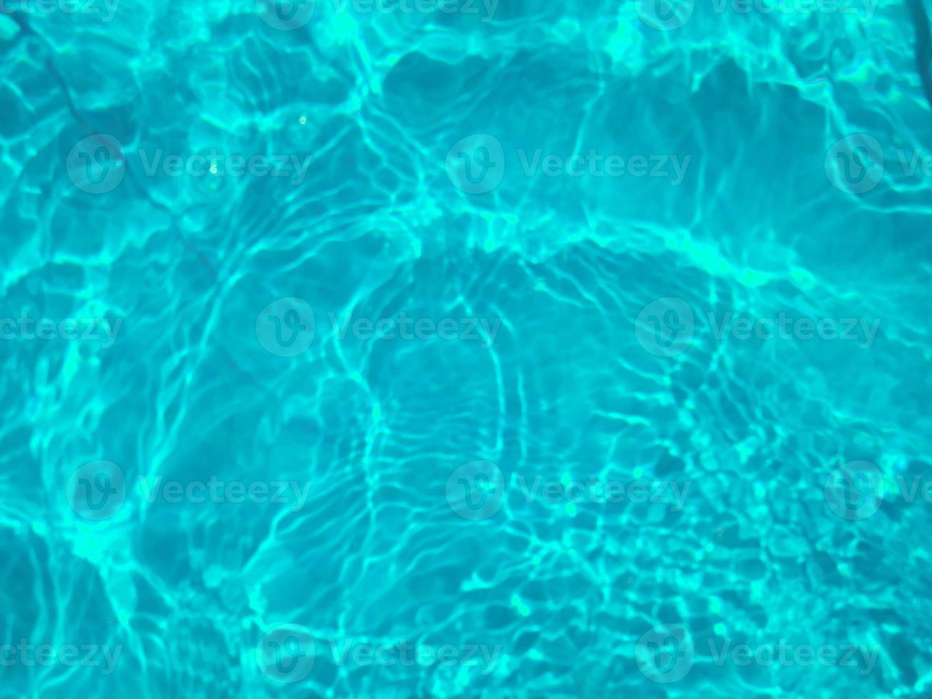 Defocus blurred transparent blue colored clear calm water surface texture with splashes and bubbles. Trendy abstract nature background. Water waves in sunlight. Blue water background. photo