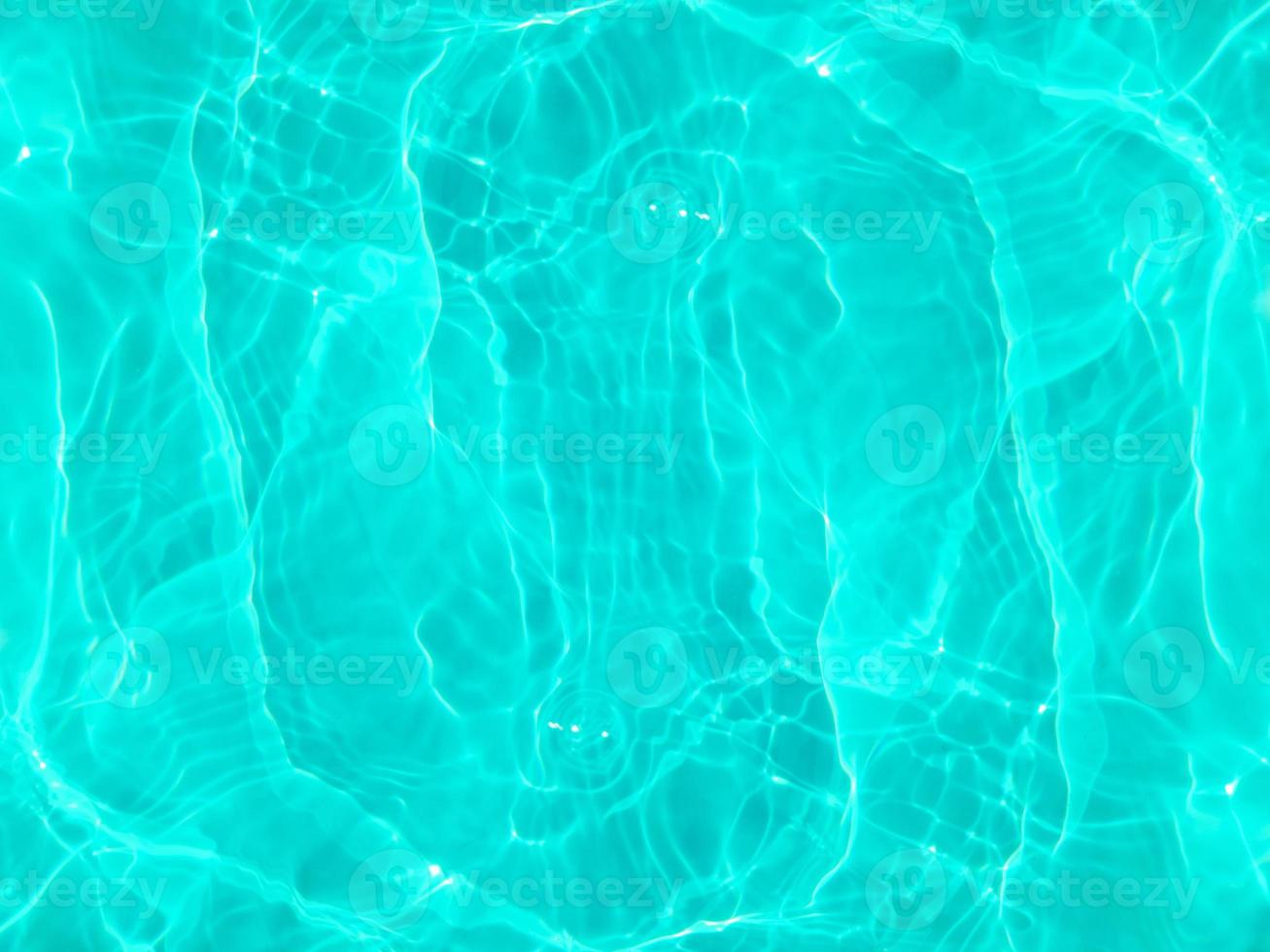 Defocus blurred transparent blue colored clear calm water surface texture with splashes and bubbles. Trendy abstract nature background. Water waves in sunlight. Blue water background. photo