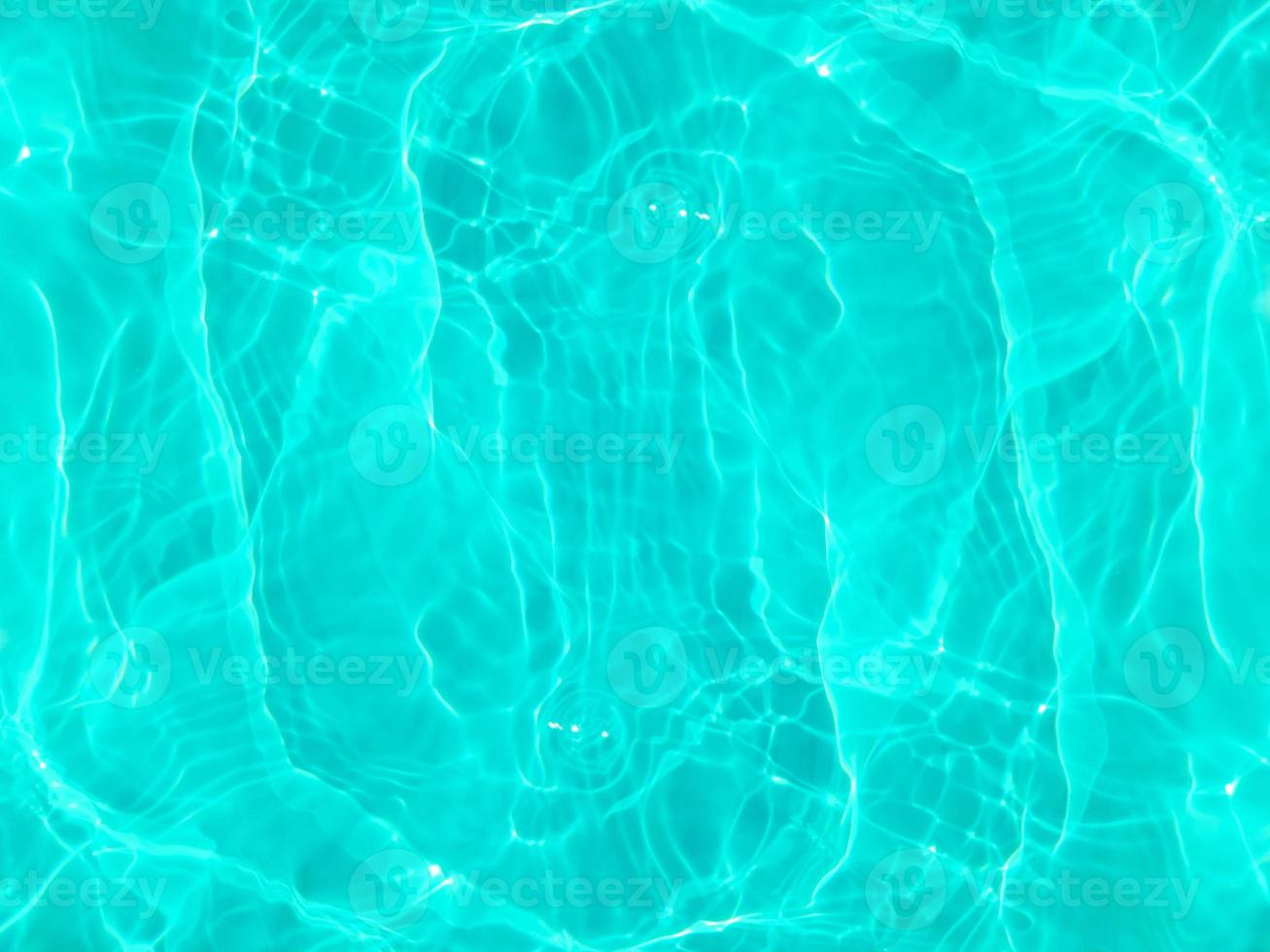 desenfoque borroso transparente color azul claro agua tranquila textura superficial con salpicaduras y burbujas. fondo de naturaleza abstracta de moda. ondas de agua a la luz del sol. fondo de agua azul. foto