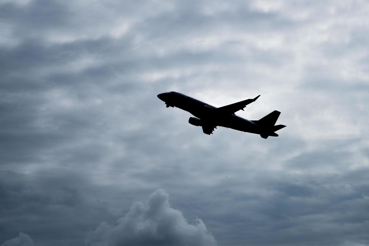 la silueta del avión vuela sobre el cielo con un fondo nublado. foto