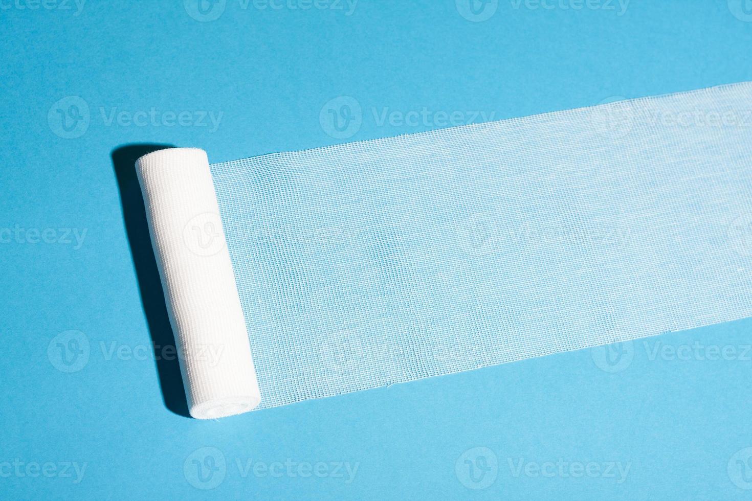 Sterile bandage roll unwound on blue background. photo