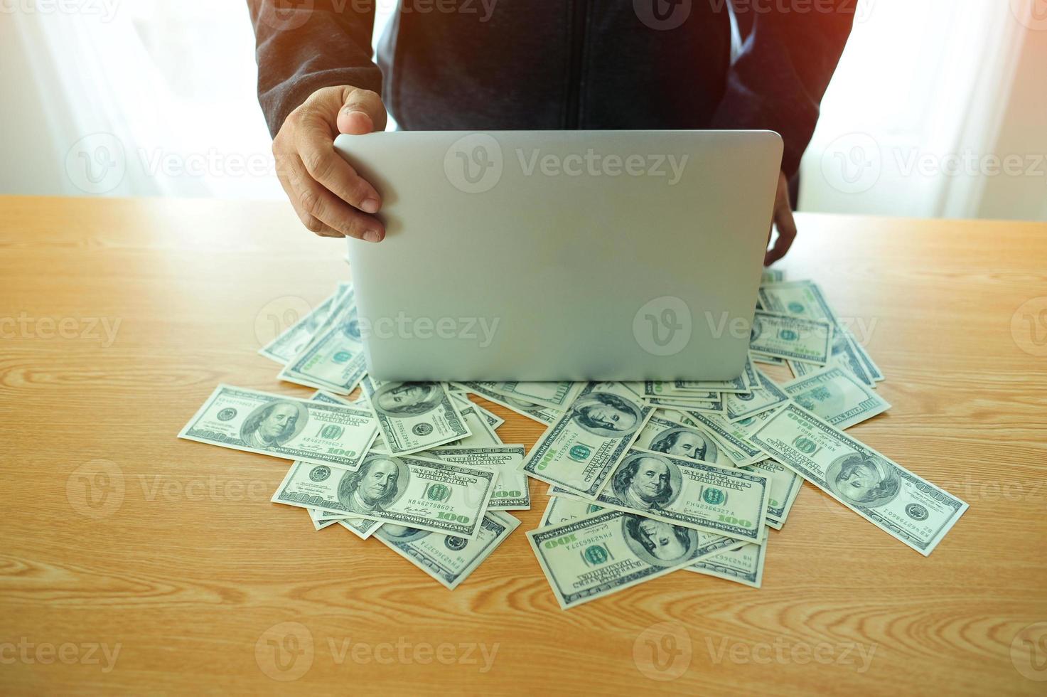 Businessman working on laptop with money on financier's desk financially successful businessman photo
