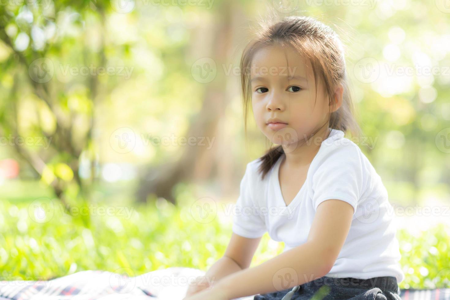 Portrait face of cute asian little girl and child happiness and fun in the park in the summer, smile and happy from asia kid and relax in the garden, lifestyle childhood concept. photo