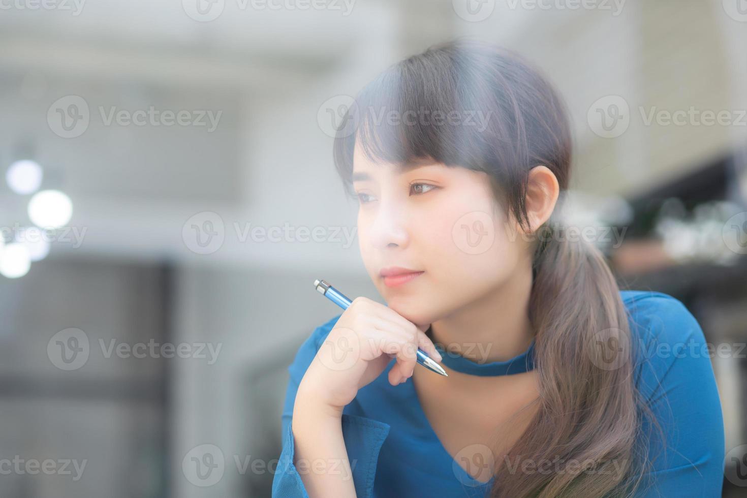Beautiful young asian woman writer smiling thinking idea and writing on notebook or diary with happy, lifestyle of asian girl is student, female planning working, education and business concept. photo