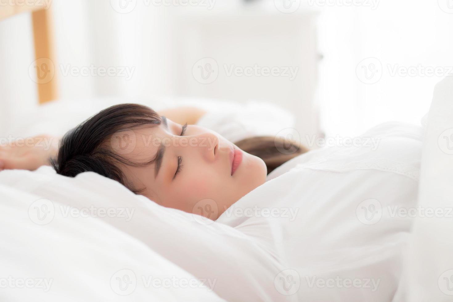 bella joven asiática durmiendo en la cama con la cabeza en la almohada cómoda y feliz. chica con relax por concepto de salud. foto