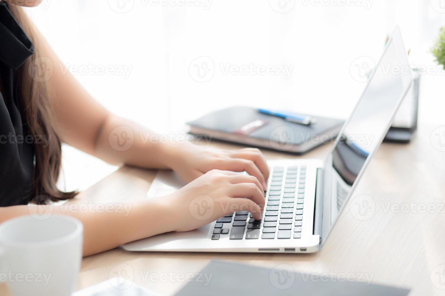 Closeup freelance asian woman working and typing on laptop computer at desk office with professional, girl using notebook checking email or social network, business and lifestyle concept. photo