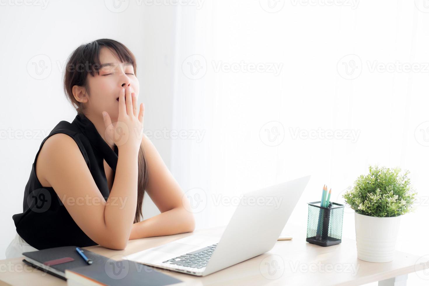 beautiful young freelance asian woman working bored and tired on laptop computer at the office, girl lazy sleepy and yawning on notebook, female secretary with exhausted, business concept. photo