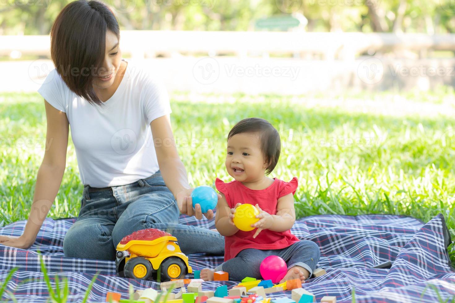 hermosa joven madre asiática e hija jugando bloques de juguete para aprender el desarrollo feliz y divertido en el parque en verano, actividad alegre de la madre y el niño juntos en el jardín en vacaciones, concepto familiar. foto