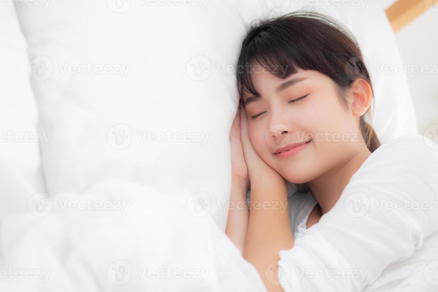 Beautiful asian young woman sleeping lying in bed with head on pillow comfortable and happy. girl with relax for health concept. photo