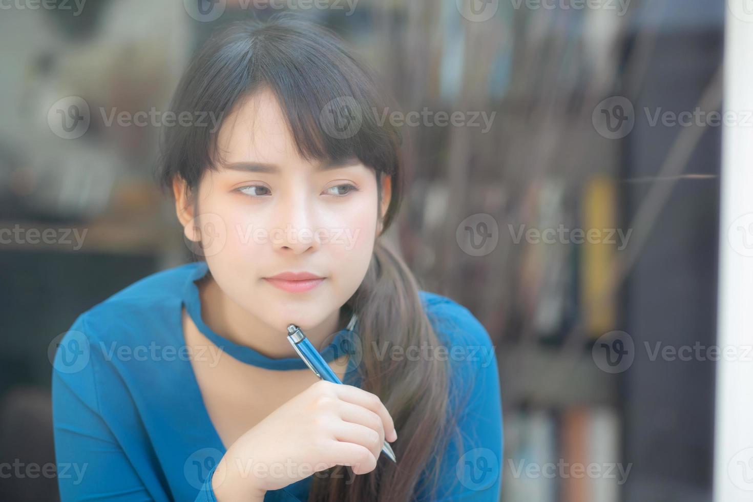 Beautiful young asian woman writer smiling thinking idea and writing on notebook or diary with happy, lifestyle of asian girl is student, female planning working, education and business concept. photo