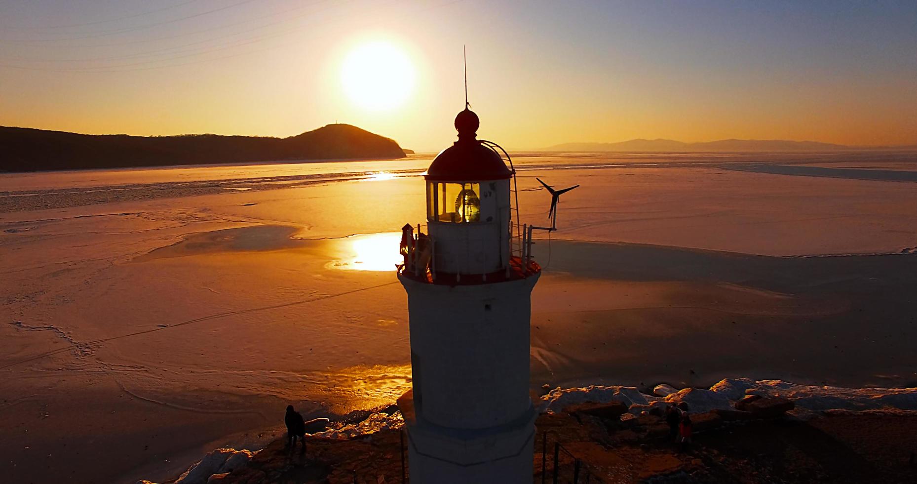 faro en el fondo de la puesta de sol. vladivostok, rusia foto