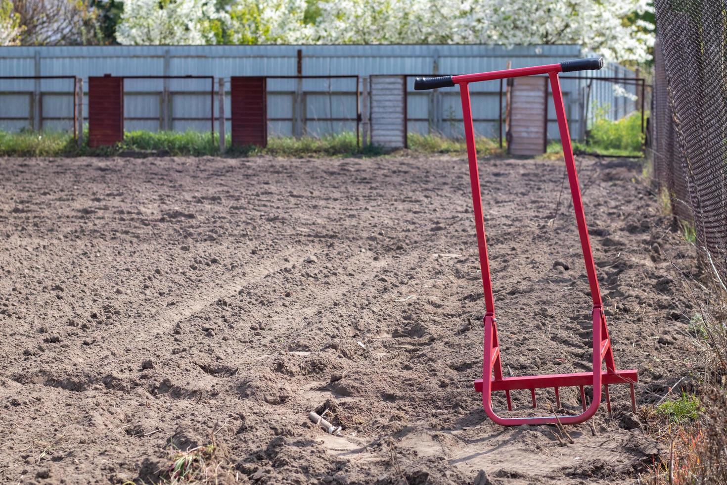 Red shovel in the form of a fork in the garden. Miracle shovel, handy tool. Manual cultivator. The cultivator is an effective tool for tillage. Bed loosening. Sustainable agricultural tools. photo