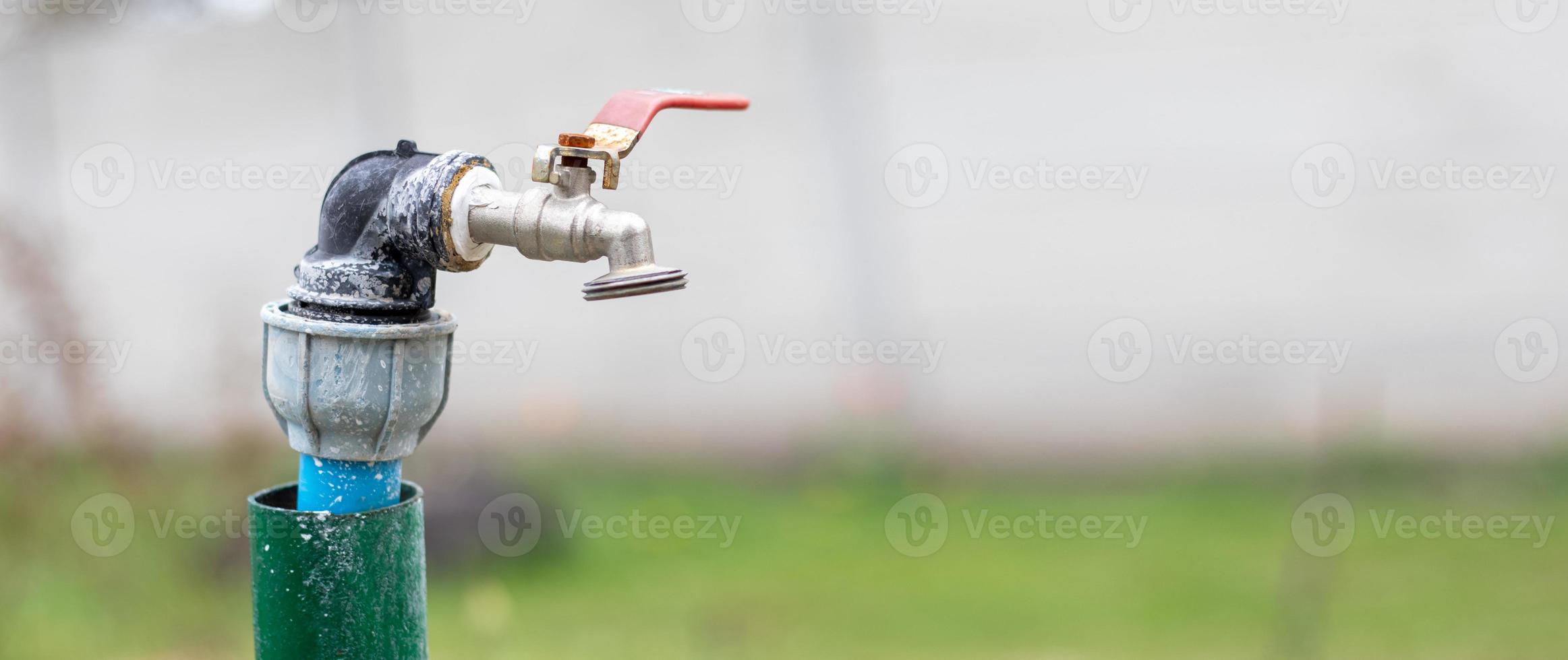 Water faucet on the background of nature. Opening or closing a faucet to save water indicates a water shortage problem. Selective focus with blurred background. Banner with copy space. photo