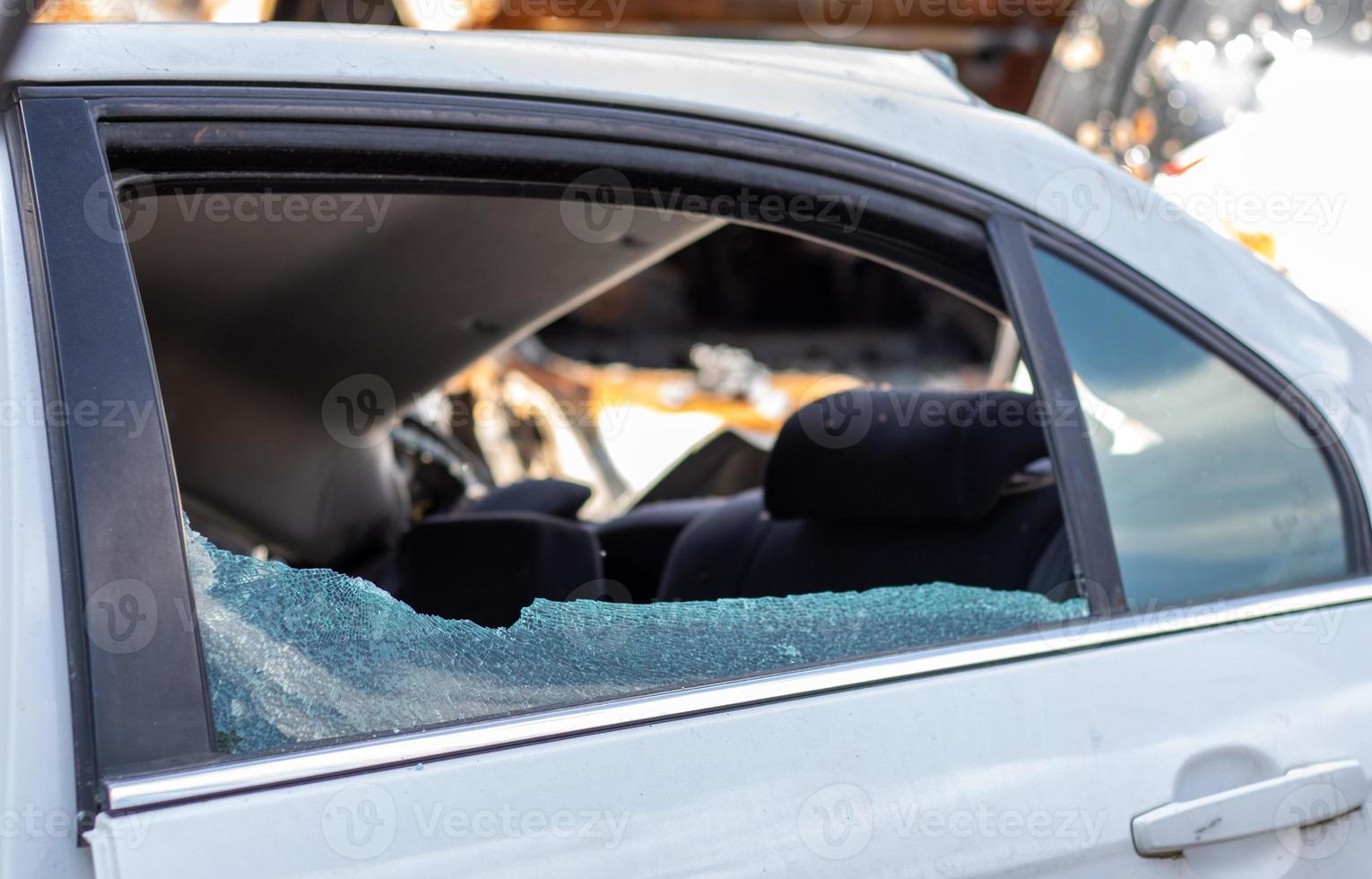 incidente delictivo irrumpir en un coche aparcado en la calle. cristales laterales rotos y el habitáculo detrás. un crimen cometido por un ladrón, robando cosas. coche después de un accidente. foto