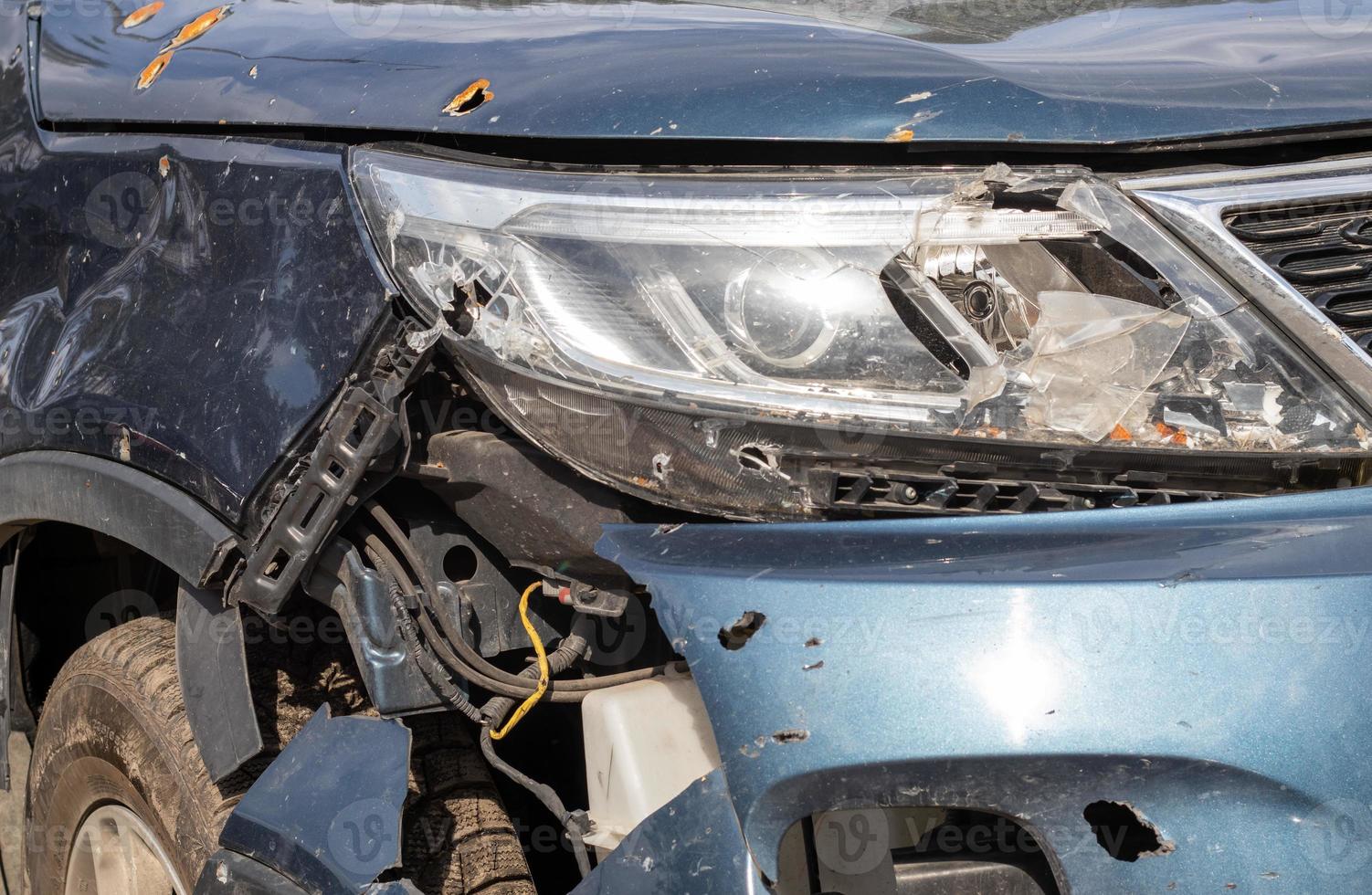 Broken headlights as a result of a collision. Broken blue car after an accident. Car accident concept. Damaged emergency headlight, hood and bumper. Damage to the car body after the accident. photo