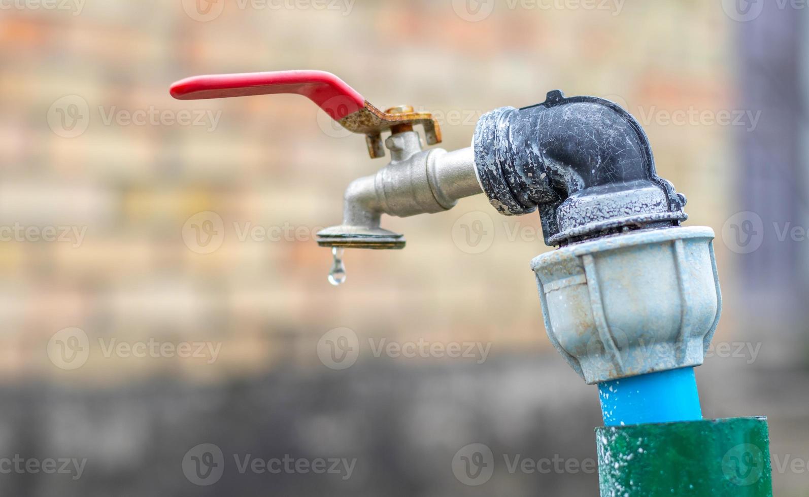 Water faucet on the background of nature. Opening or closing a faucet to save water indicates a water shortage problem. Rustic fountain with daylight. Selective focus with blurred background. photo