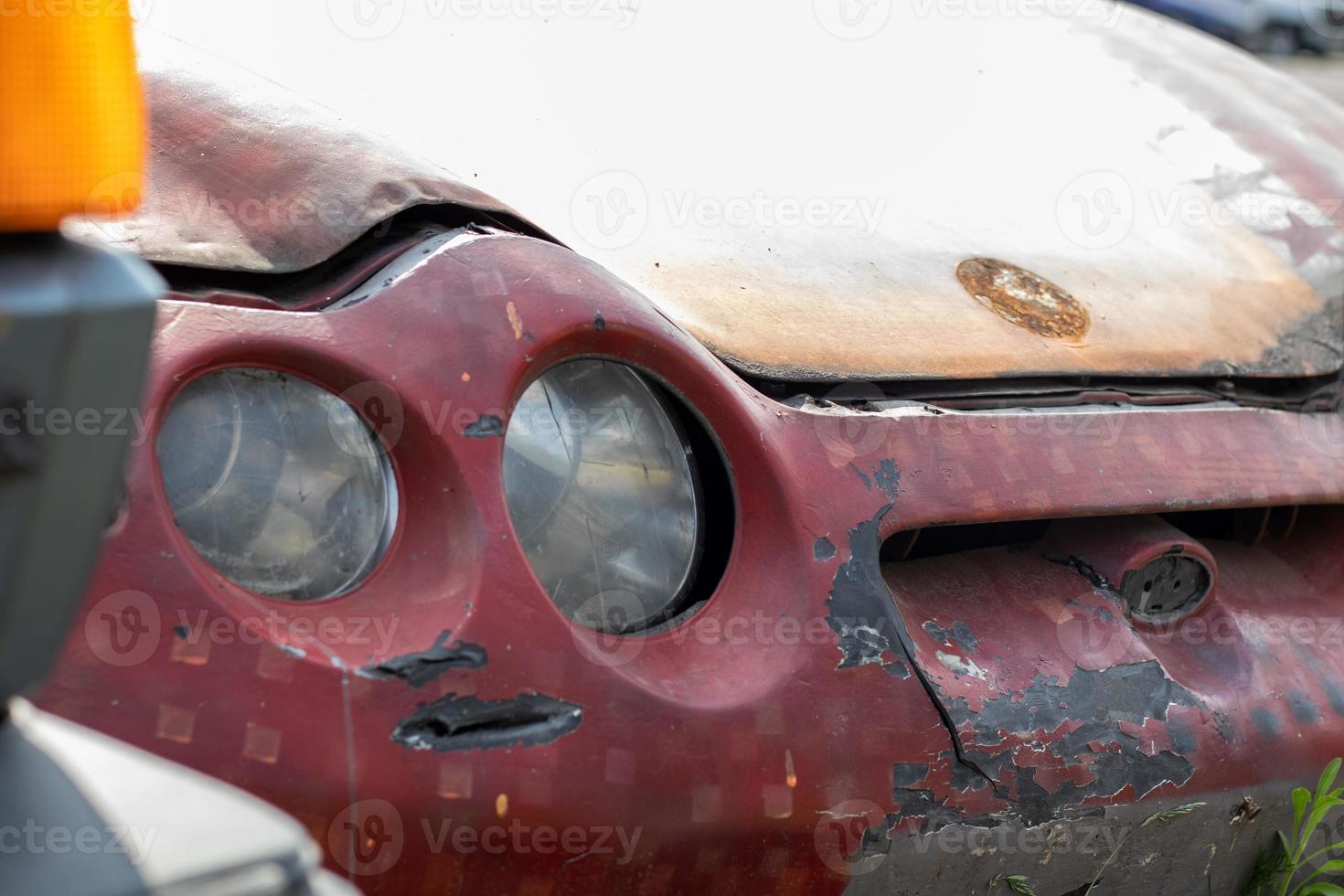 Broken headlights as a result of a collision. Broken red car after an accident. Car accident concept. Damaged emergency headlight, hood and bumper. Damage to the car body after the accident. photo