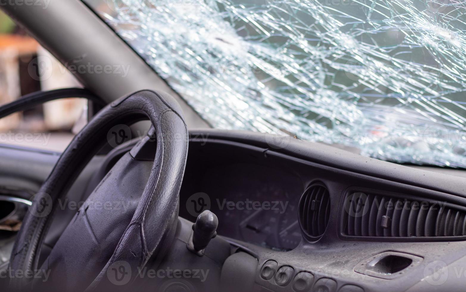 Close-up of the steering wheel of a car after an accident. The driver's airbags did not deploy. Soft focus. Broken windshield with steering wheel. Vehicle interior. Black dashboard and steering wheel. photo
