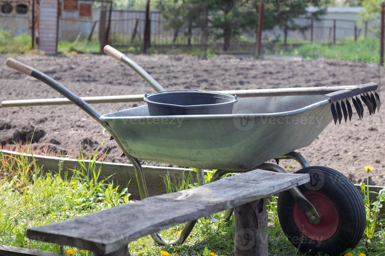 Gray metal garden wheelbarrow with two handles and one wheel. The wheelbarrow is in the garden or garden. Gardener's wheelbarrow in the backyard. Garden cleaning. photo