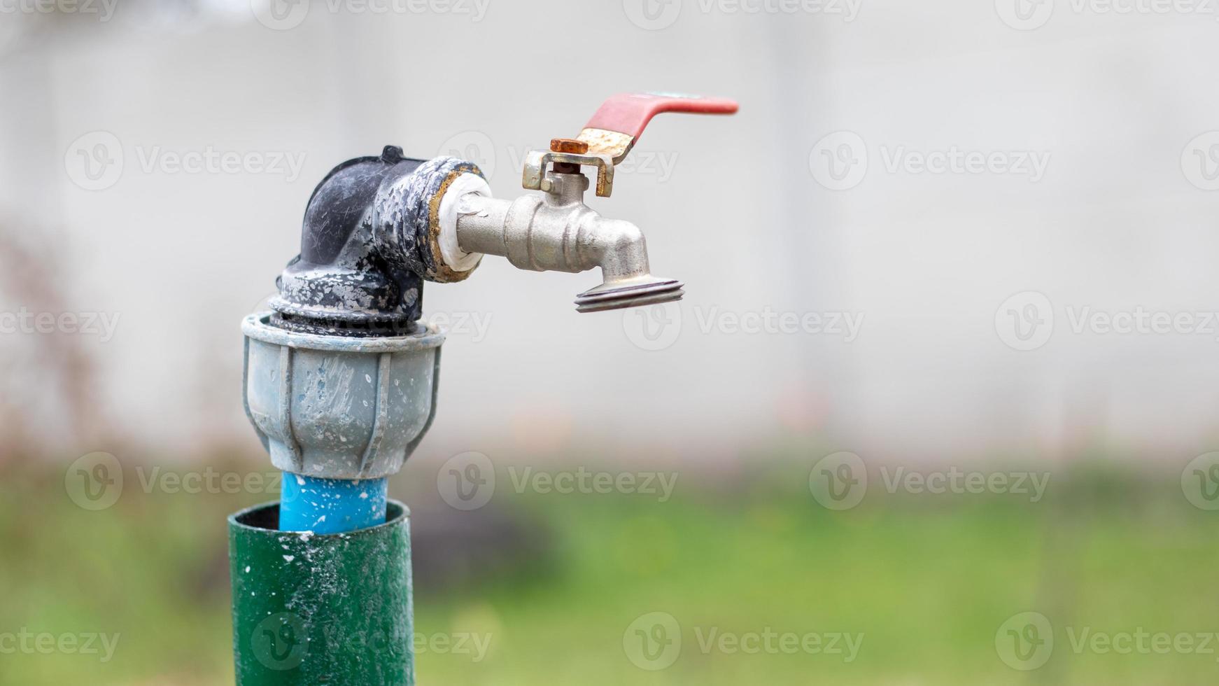 Water faucet on the background of nature. Opening or closing a faucet to save water indicates a water shortage problem. Rustic fountain with daylight. Selective focus with blurred background. photo