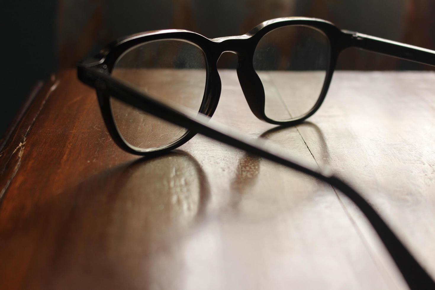 Primer plano de enfoque superficial de gafas transparentes incoloras sobre una mesa de madera foto