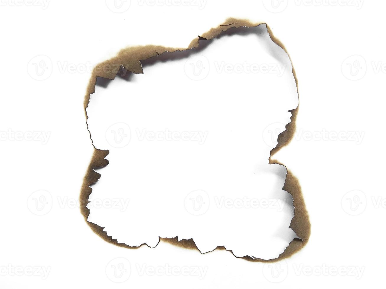 Hole paper with burned edges on white background photo