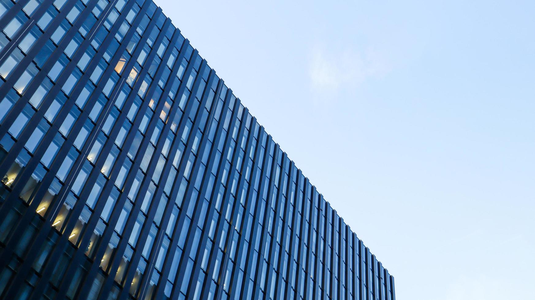 moderno edificio de gran altura contra el cielo azul. vista inferior de un rascacielos en el distrito de negocios. vista de ángulo bajo de la fachada de vidrio de un edificio de oficinas. foto