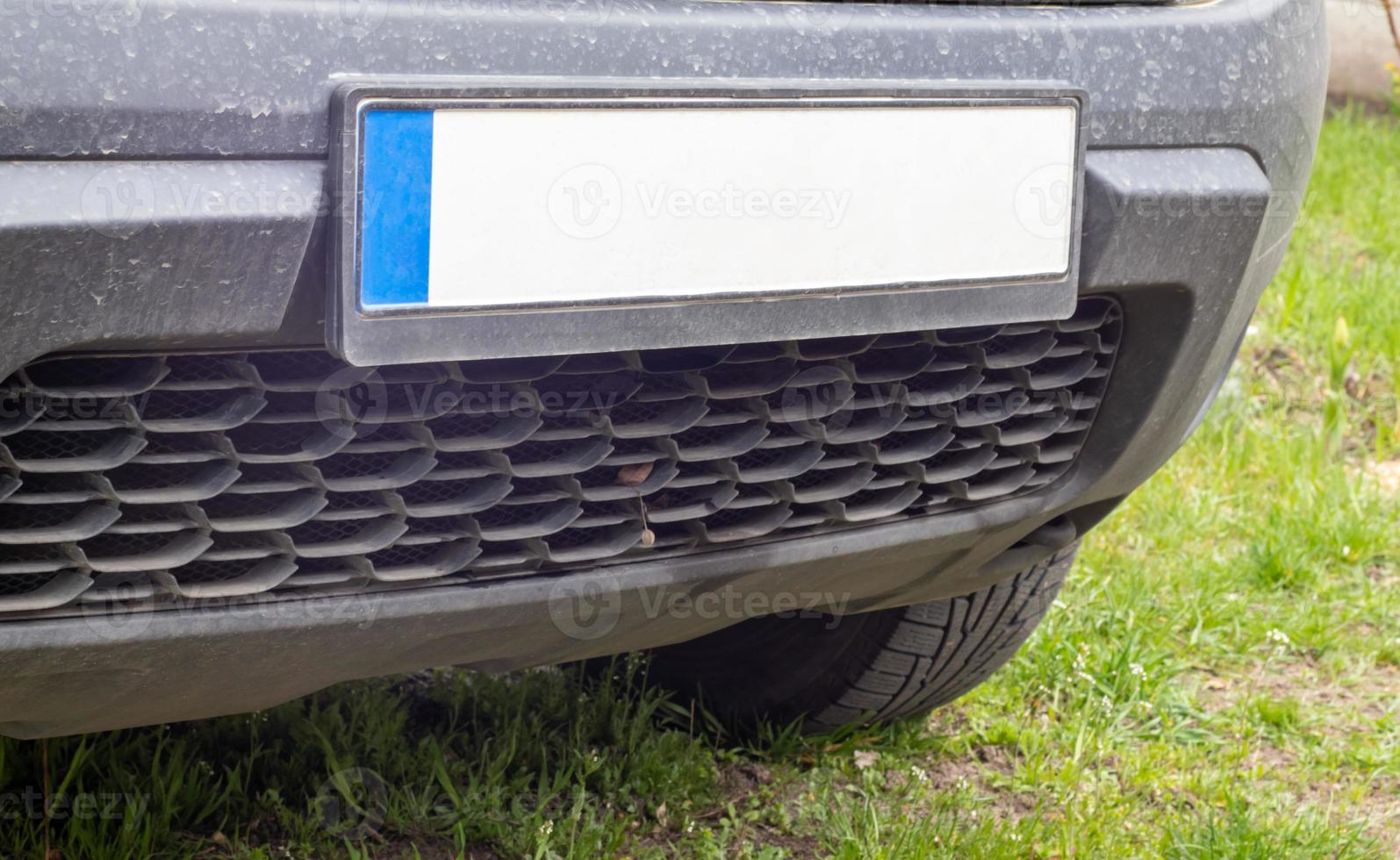 número de coche sin letras ni números en el parachoques del coche. matrícula blanca en blanco delante del coche, todos los logotipos eliminados, cerrar. la matrícula rectangular delantera de un vehículo en la calle. foto