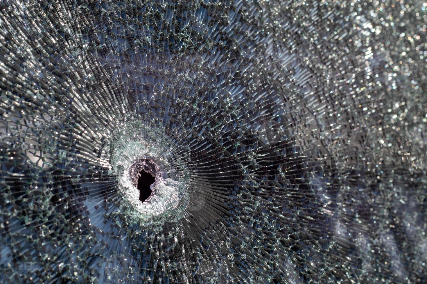 Holes on the windshield of the car, it was shot from a firearm. Bullet holes. Smash car windshield, broken and damaged car. The bullet made a cracked hole in the glass. photo